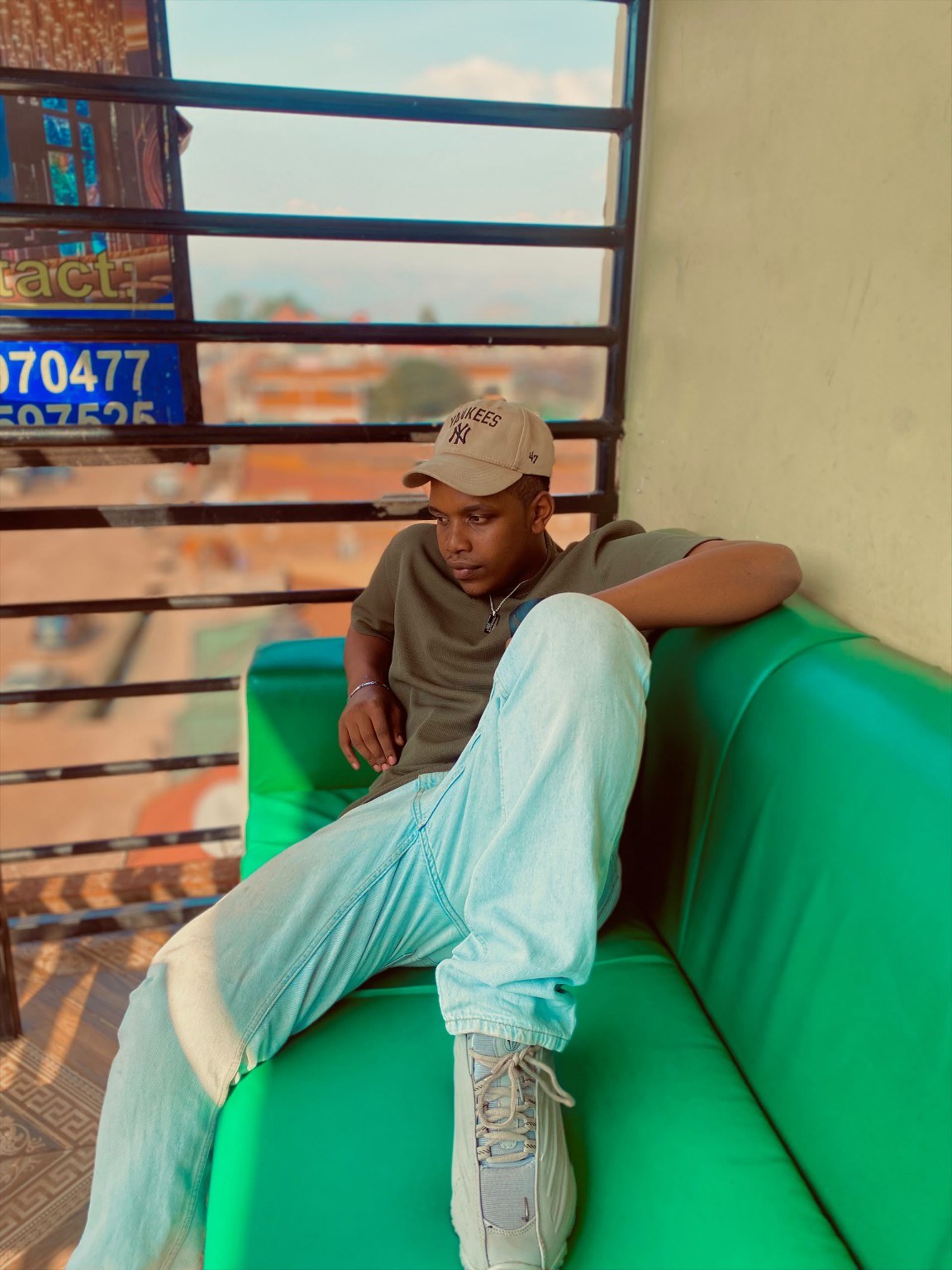 Amza seated on a green sofa